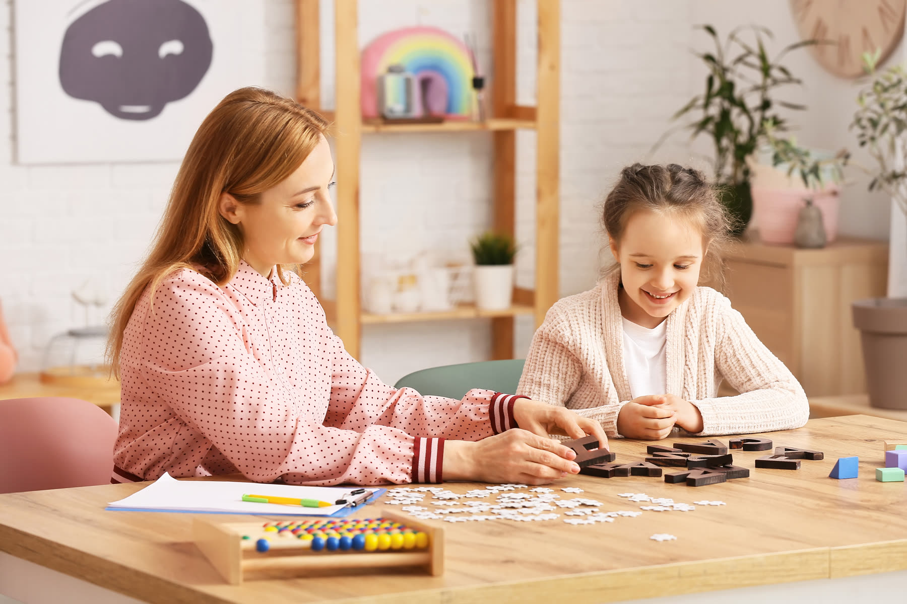 A specialist working through table activities with a young girl