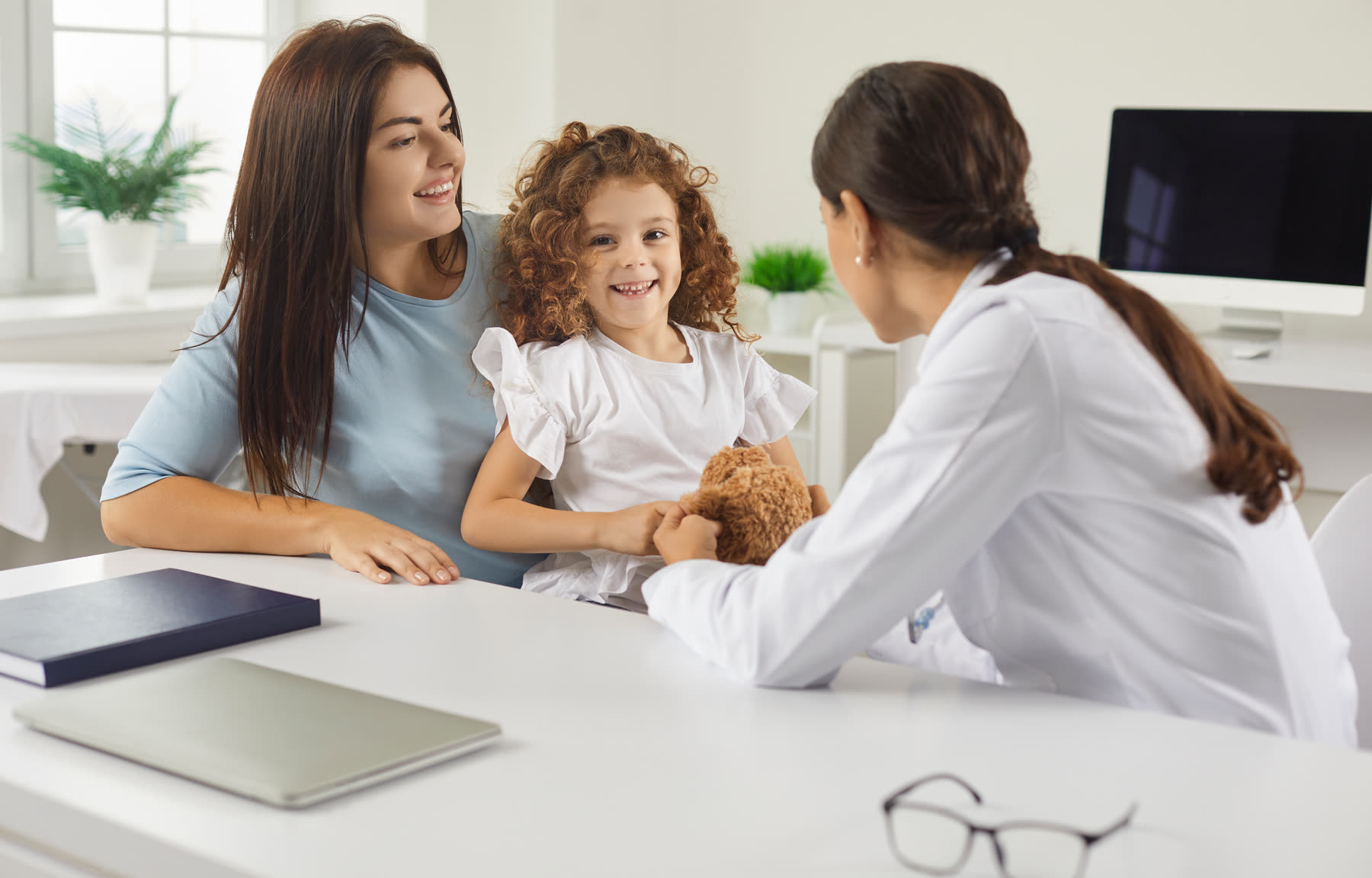 A mother and her smiling daughter talking with a clinician