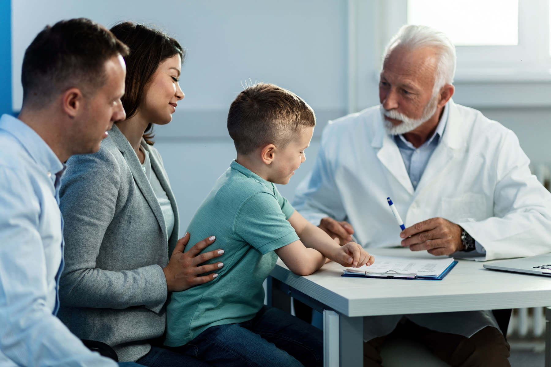 Parents and their young son meeting with a doctor at a table