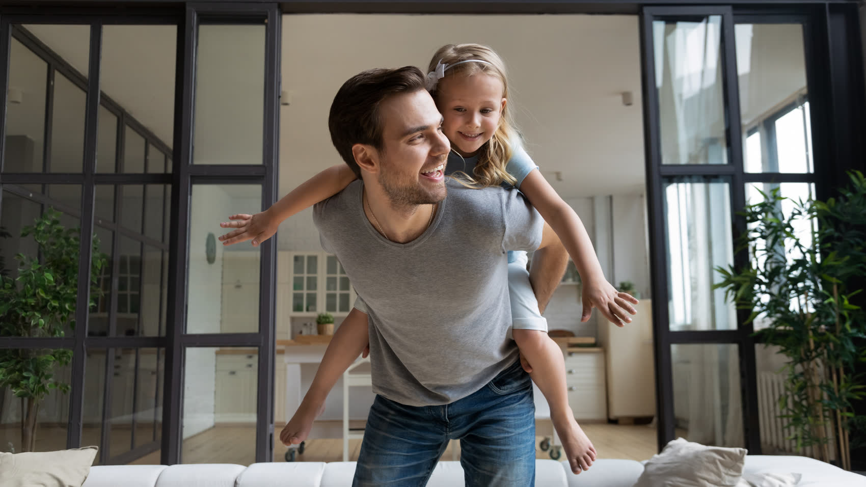 A laughing father playing with his daughter at home