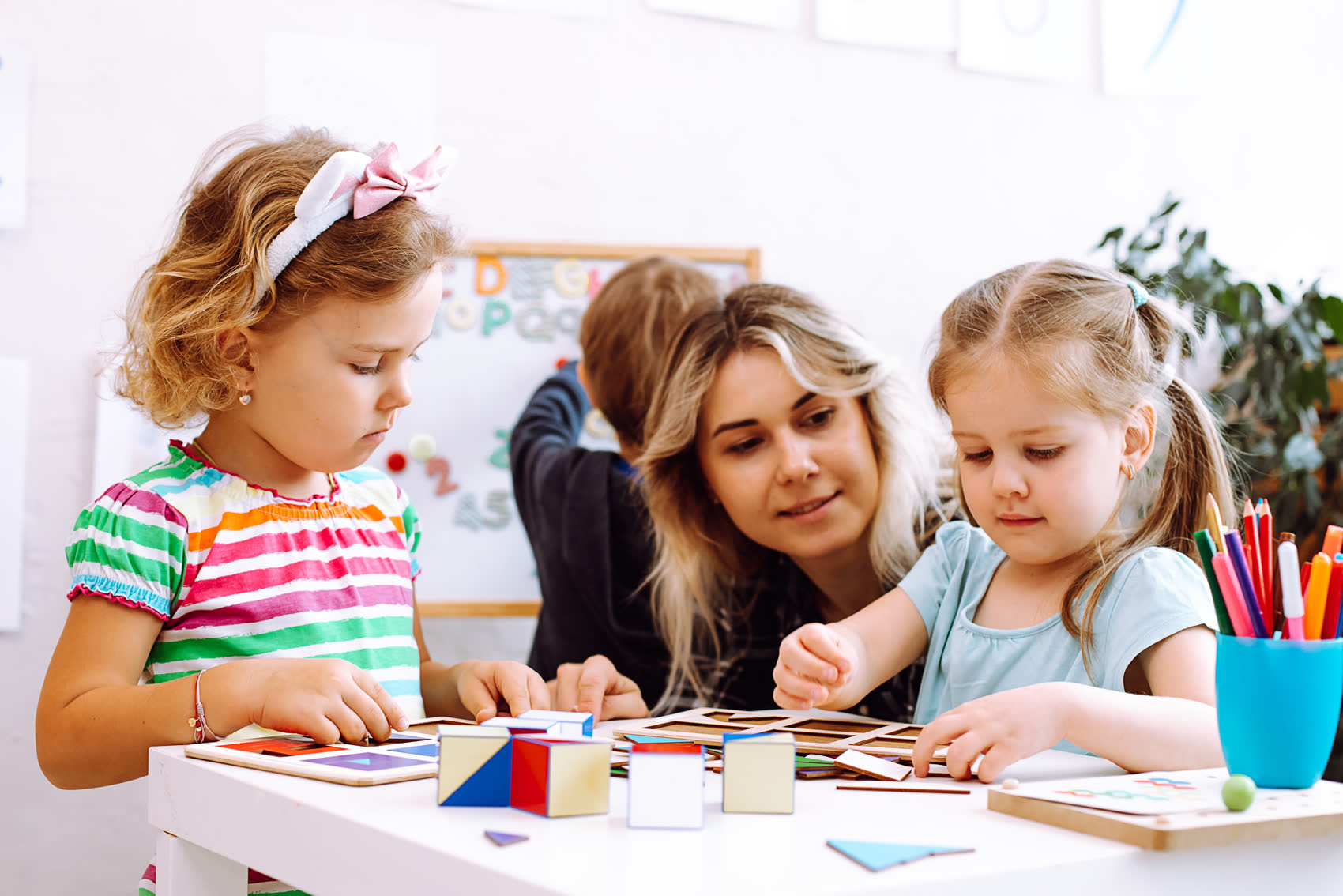 Two young girls stacking colorful cubes at a classroom table