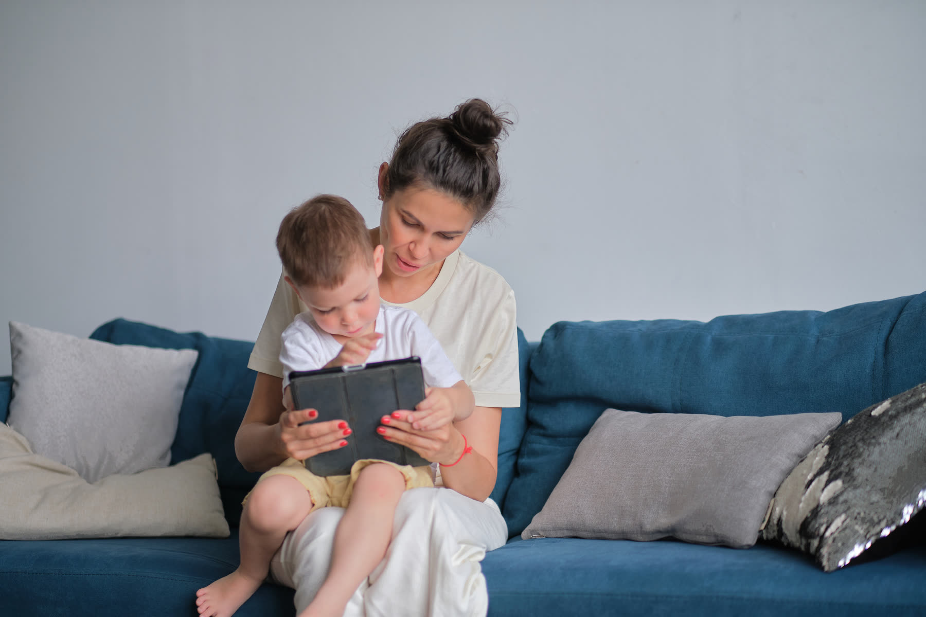A mother with her toddler on her lap, using a tablet