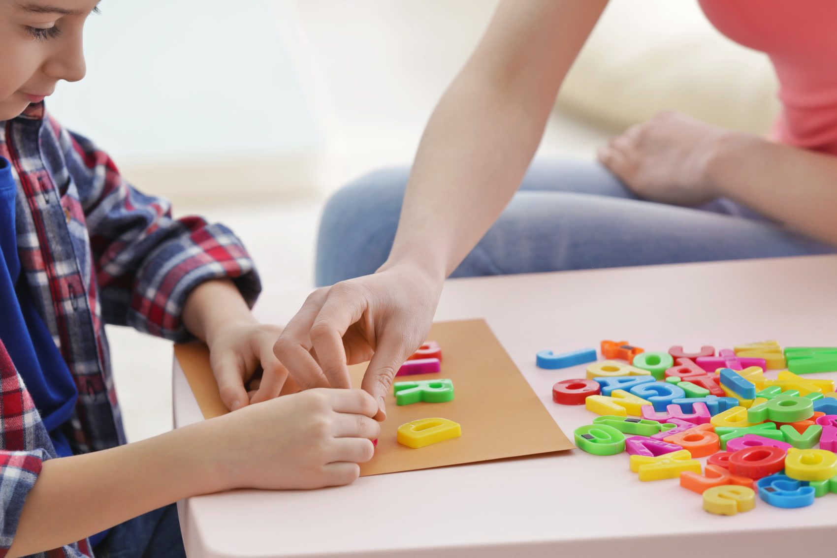 A child sorting colorful letters with a therapist helping
