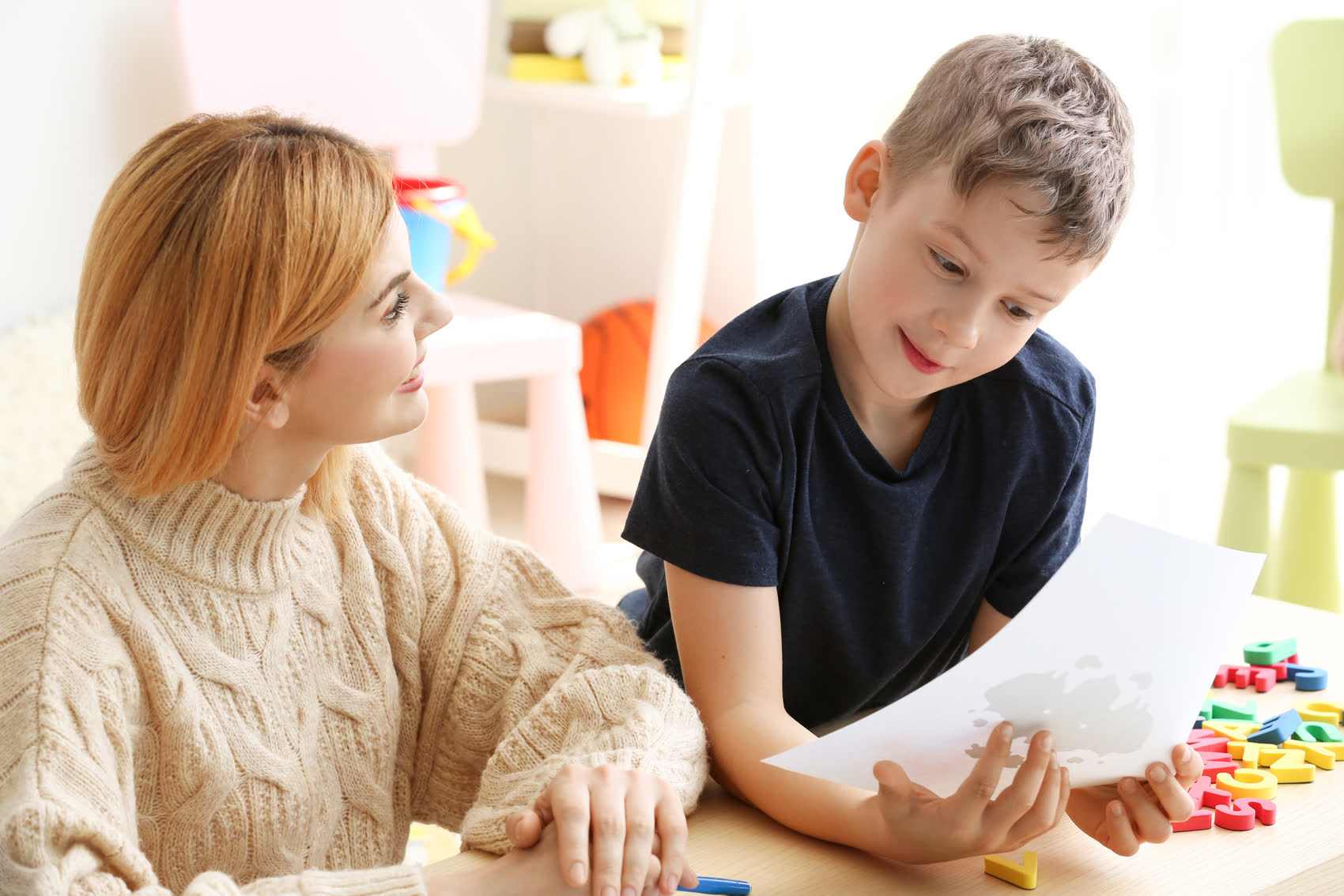 A therapist working one-on-one with a young boy at a table
